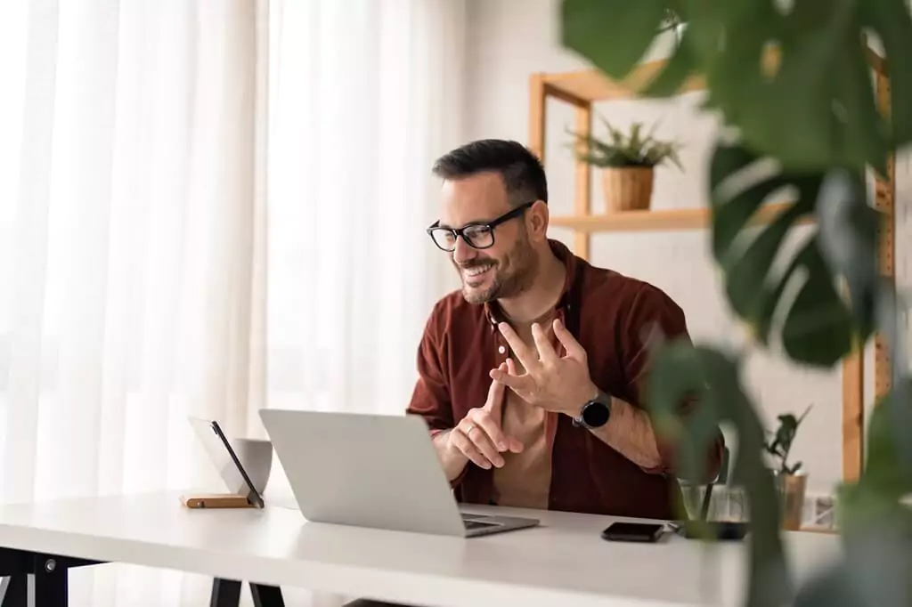 rapaz sorrindo e falando com alguém por computador