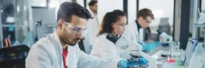 pessoas em laboratório mexendo com microscópio