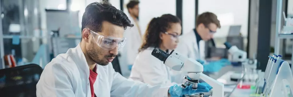 pessoas em laboratório mexendo com microscópio