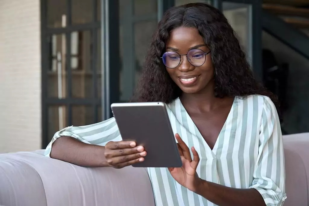 mulher lendo em tablet sentada no sofá