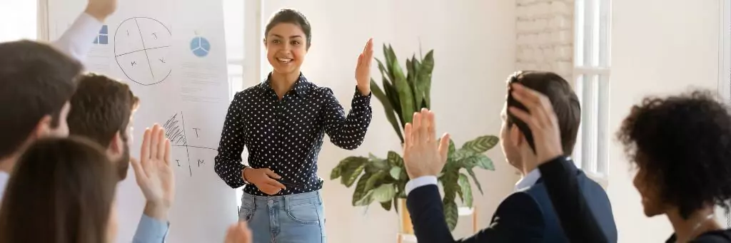 moça em reunião com colegas levantando a mão