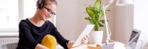 moça estudando com caderno, fone de ouvido e computador