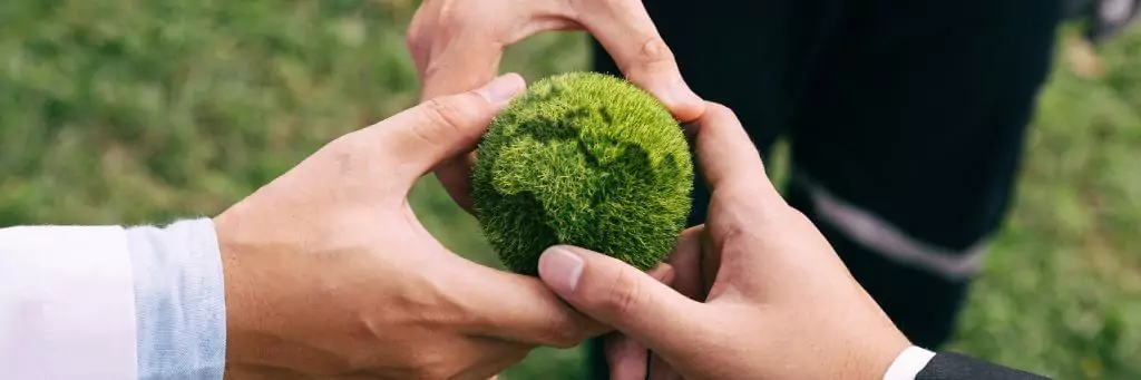 homens segurando modelo de planeta com grama